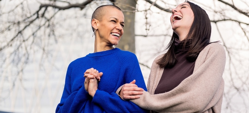 Two women laughing and walking together outdoors.