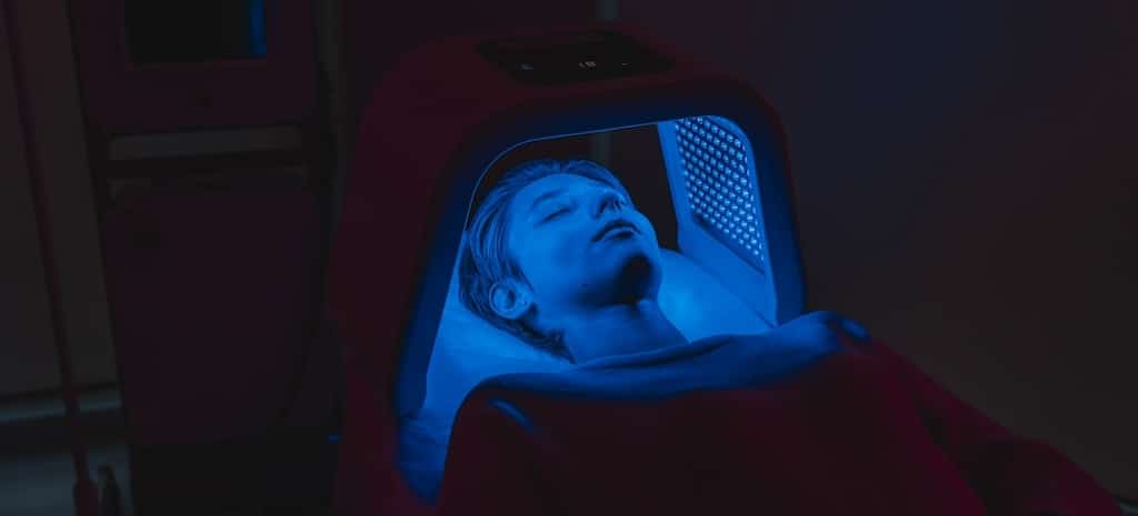 A person undergoes blue light therapy while lying inside a treatment device