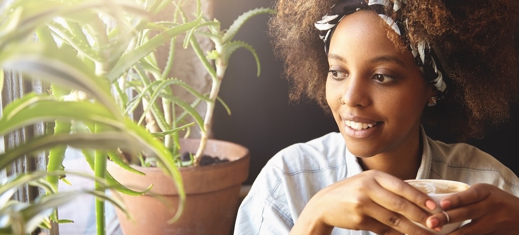 Portrait of young girl with nose-ring and do-rag on her head, enjoying hot coffee or tea,