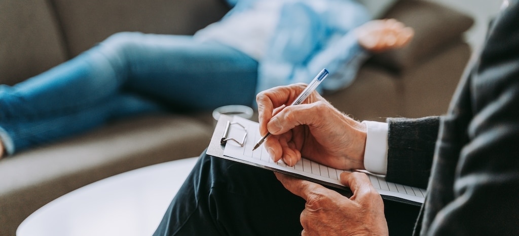 Behavioral health professional taking notes during counseling session.