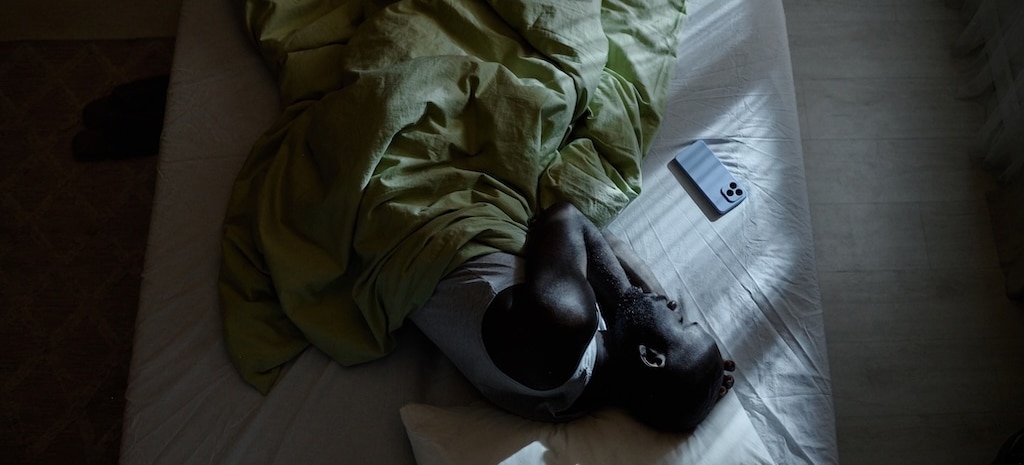 Photo of man lying in bed struggling to sleep, dealing with anxiety from drinking.