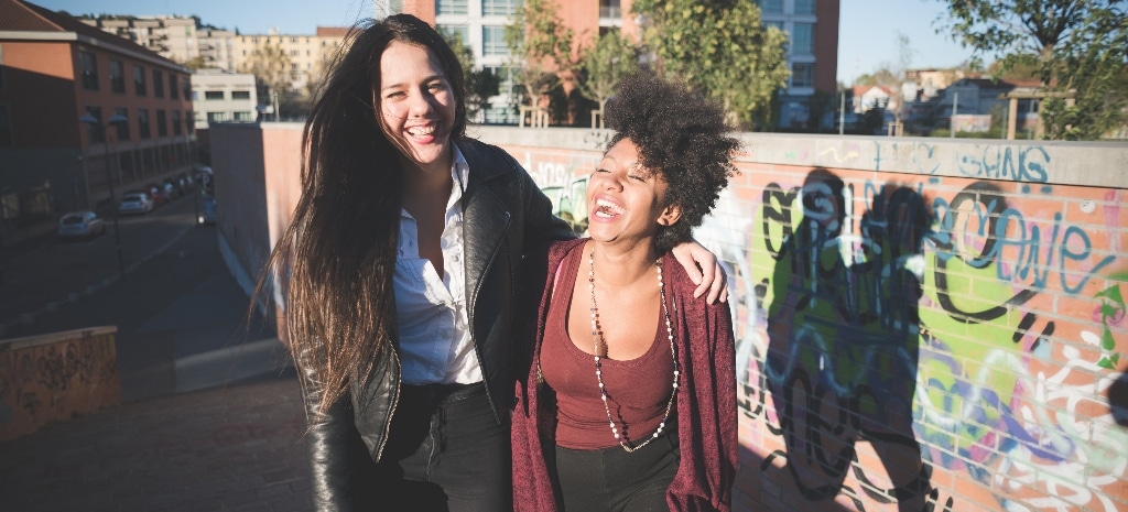 two young women outdoor hugging walking in the city having fun - fooling around, friendshp, happiness concept in recovery from addiction