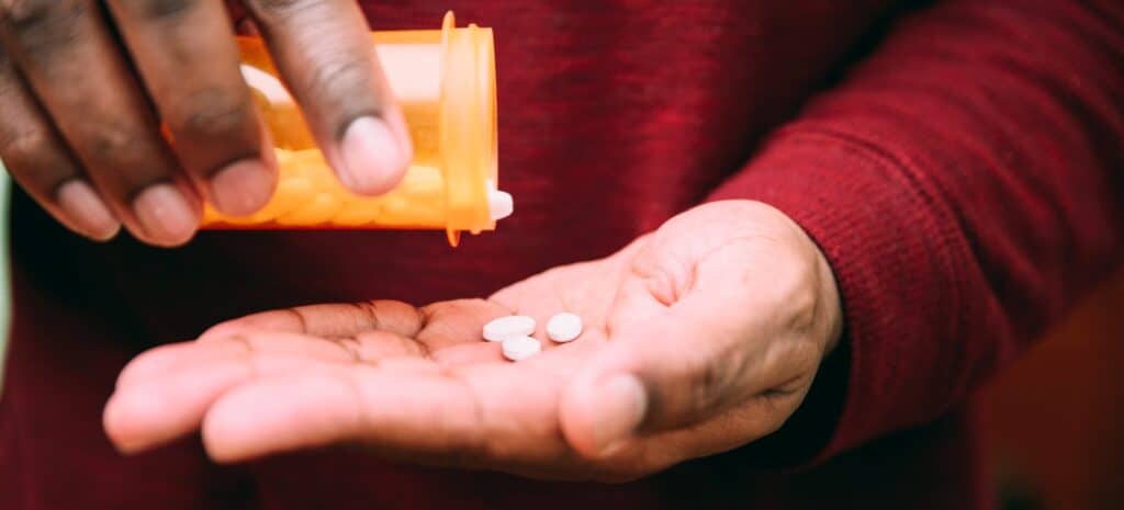 Man putting pills into his hand, representing suboxone, medication assisted treatment