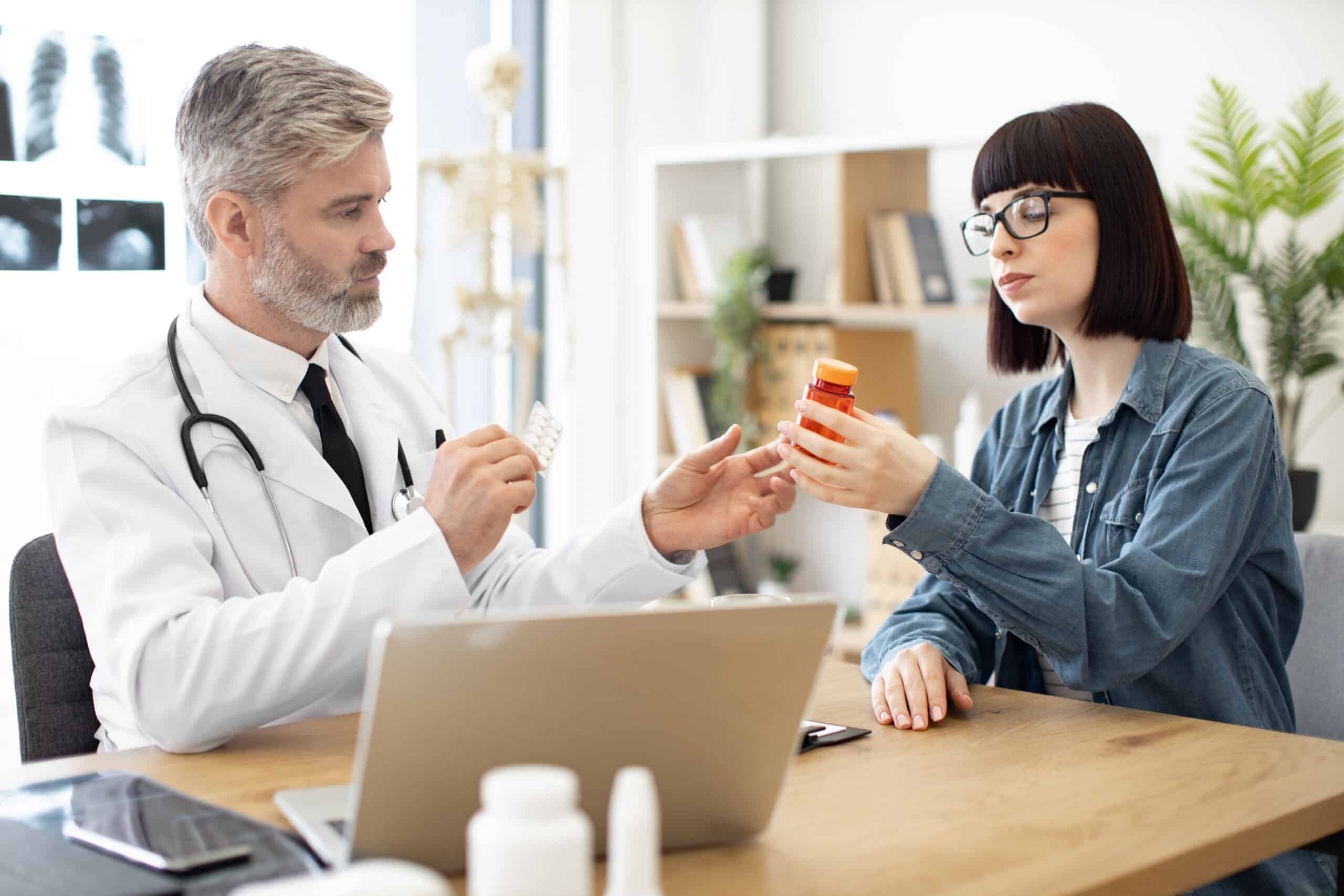 A doctor and patient looking at a bottle of pills while discussing subutex vs suboxone.
