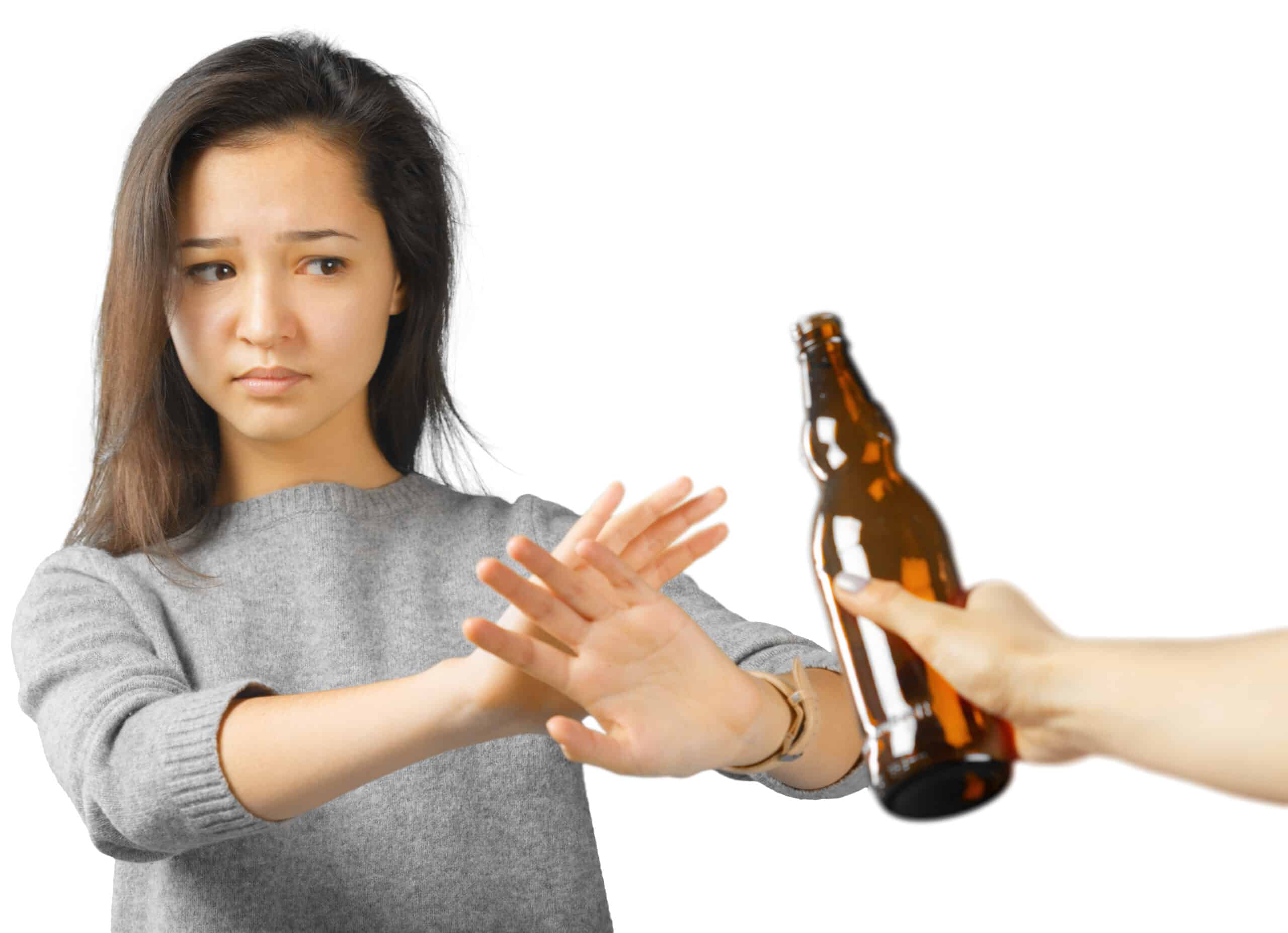 A woman who is staying sober saying no to a bottle of alcohol.