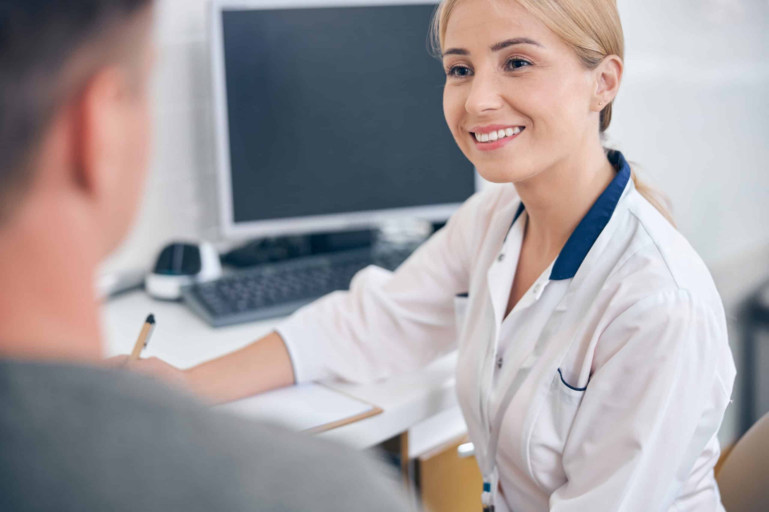 A female doctor smiling at a male patient while talking about how to qualify for suboxone.