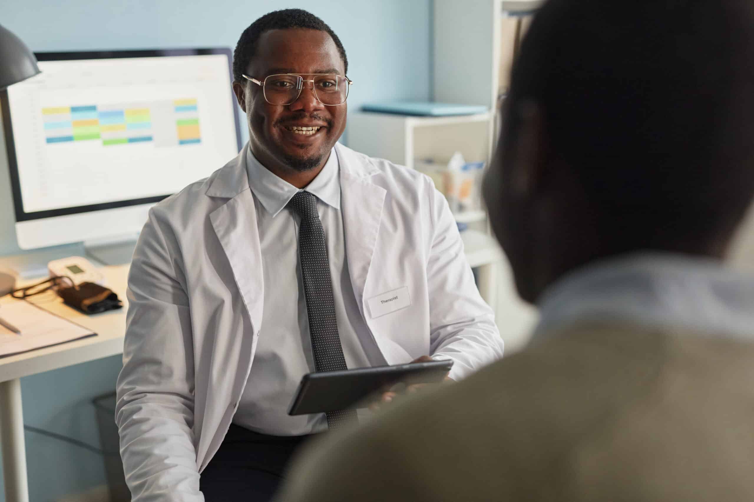A doctor smiling at a patient while answering the question does insurance cover suboxone.
