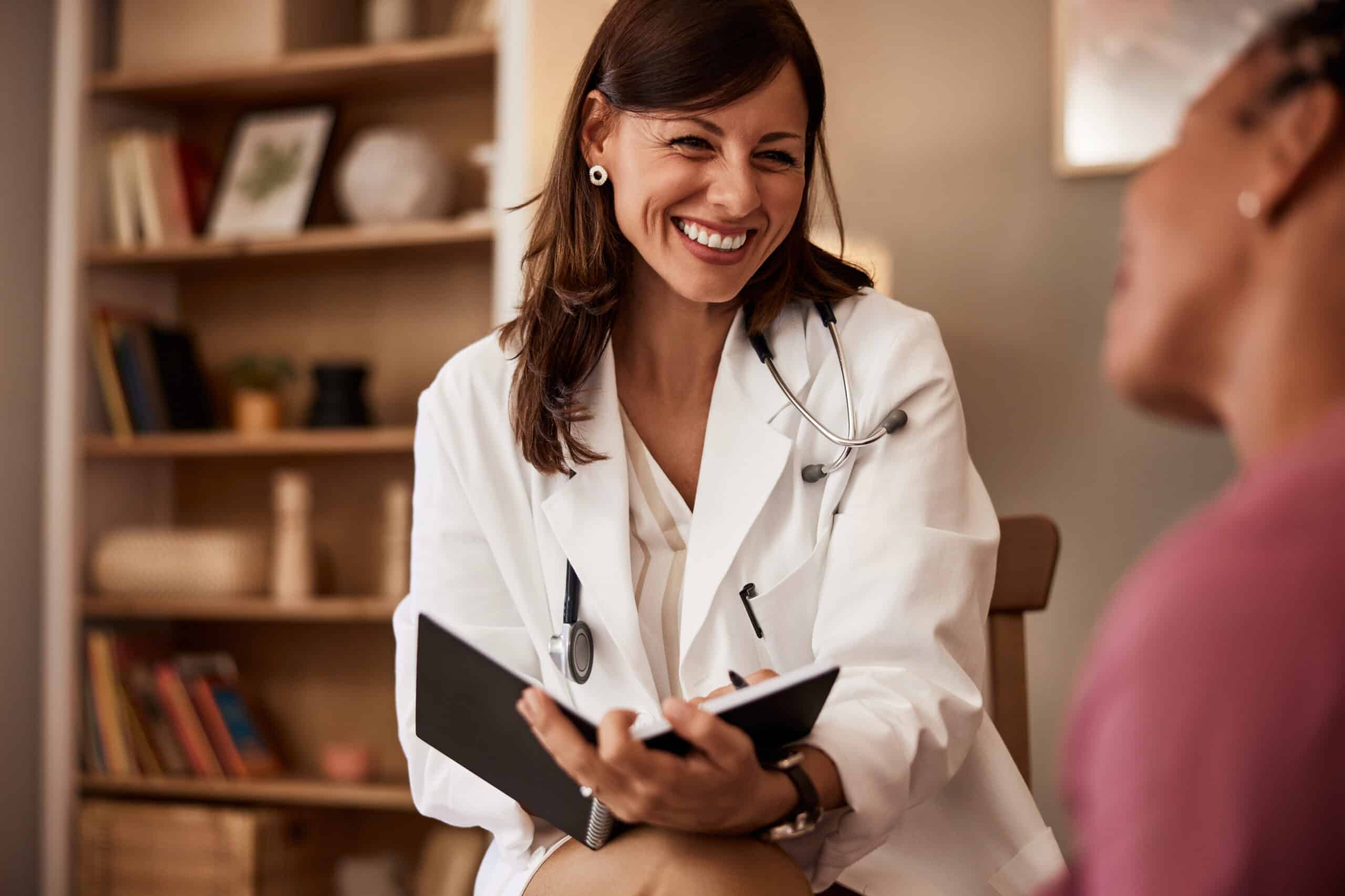 A doctor holding a folder and smiling at a patient while talking about suboxone for opioid dependence.
