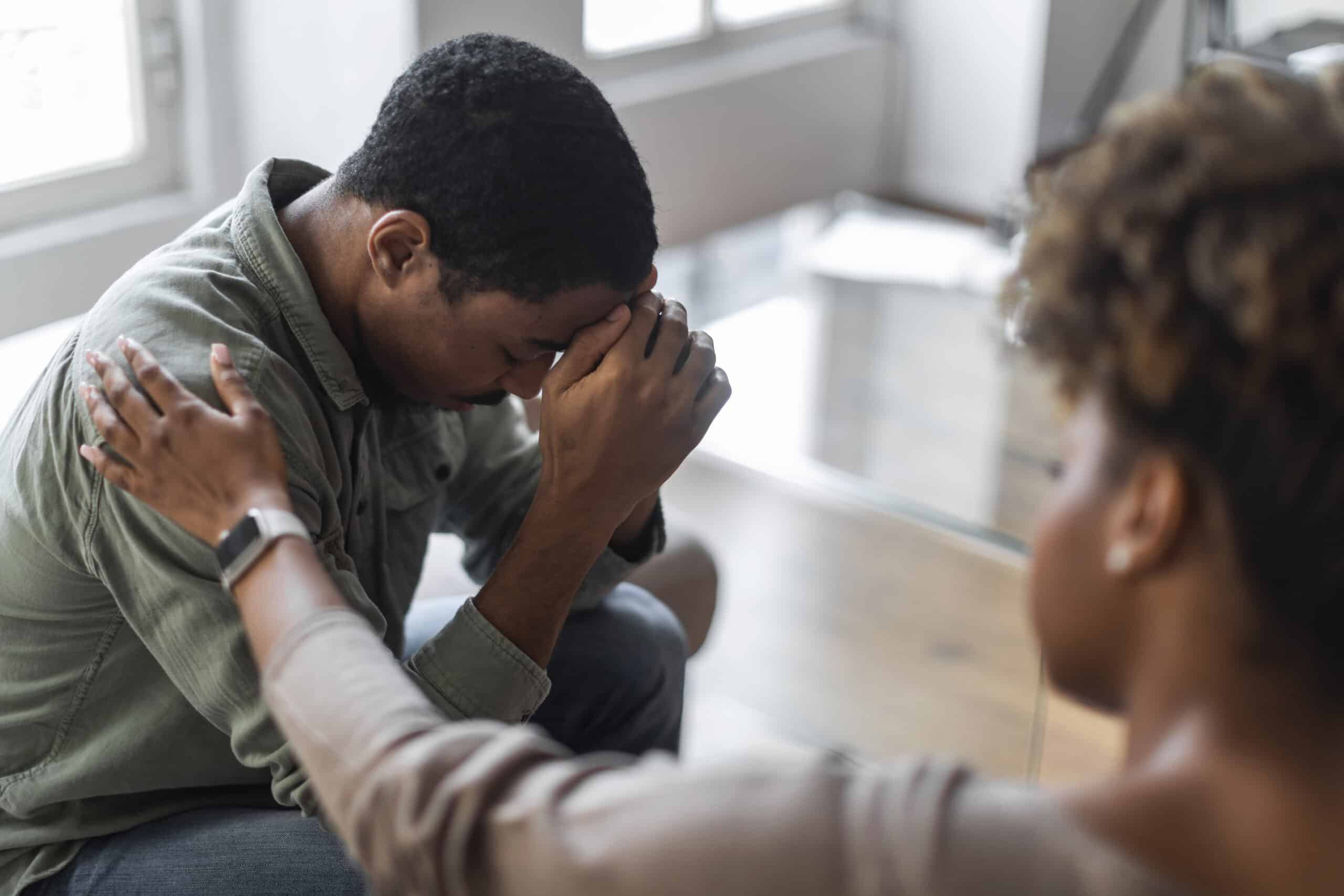 A woman placing her hand on her friend's shoulder while he is going through withdrawal for the topic suboxone for detox.